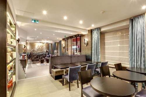 a restaurant with tables and chairs in a room at Hotel d'Amiens in Paris