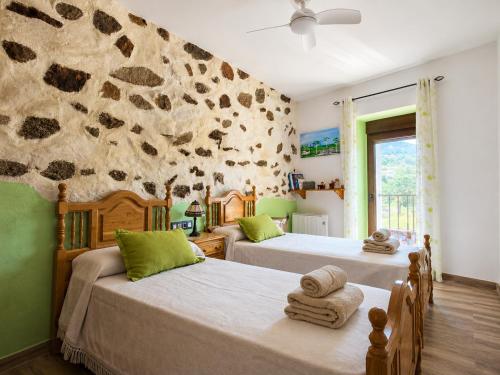 a bedroom with two beds and a stone wall at El Triskel de Chumbea- Confort y naturaleza en la Sierra de Béjar in Navalmoral de Béjar