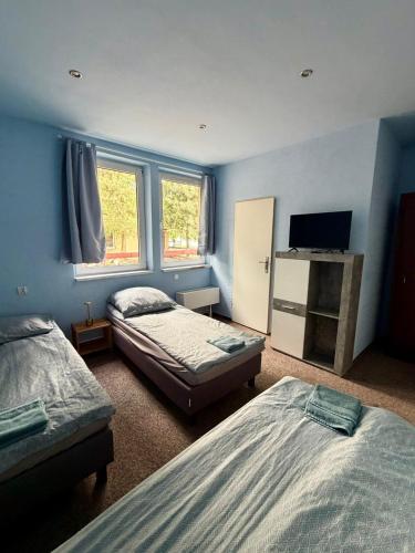 a bedroom with two beds and a flat screen tv at Pokoje przy Żaglach in Rybnik