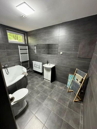 a bathroom with a tub and a toilet and a sink at Pokoje przy Żaglach in Rybnik