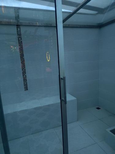a glass shower door in a room with a window at Magic Garden Luxury Pent-house in Bello