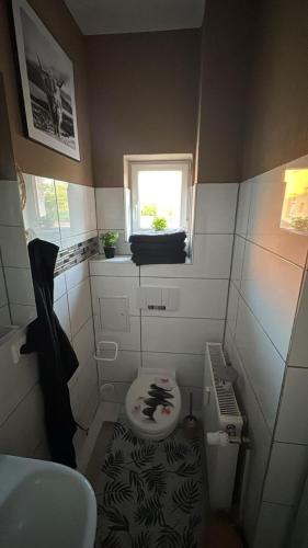 ein kleines Badezimmer mit Toilette und Fenster in der Unterkunft Stadtoase 3 in Wittenberge