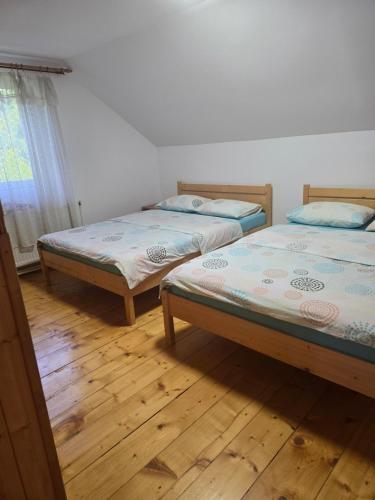two beds in a room with wooden floors at The Wooden House in Moldoveneşti