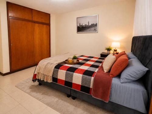a bedroom with a bed with a checkered blanket at Apartamento 2 hab en el Centro de la Ciudad wifi in Duitama