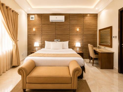 a bedroom with a bed and a chair and a desk at Grand Bohabs Hotel in Abuja