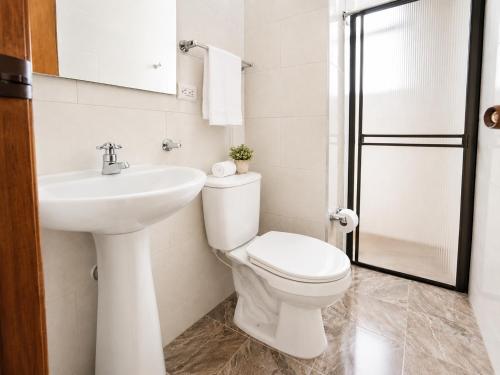 a white bathroom with a toilet and a sink at Apartamento 2 hab en el Centro de la Ciudad wifi in Duitama