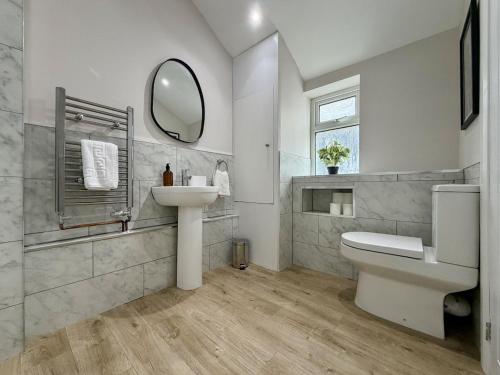 a white bathroom with a sink and a mirror at Hazel, Spacious 3-Bed Home in Dowlais