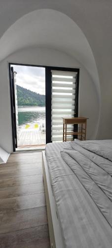 a bedroom with a bed and a large window at La Coca Lake House in Bicaz