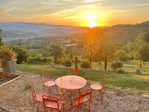 a table and chairs with the sunset in the background at Domaine des Druides in Apt