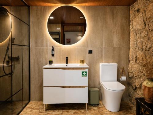a bathroom with a sink and a toilet and a mirror at Open Space com Jacuzzi a 5 mn do centro de Lamego in Lamego