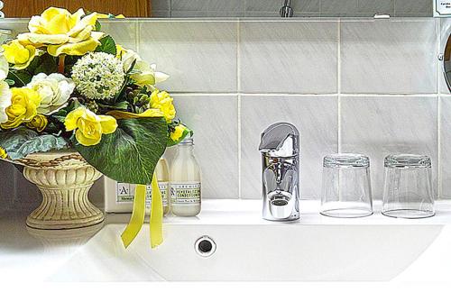 un lavandino con un vaso con fiori gialli sopra di Hotel Falter a Hof