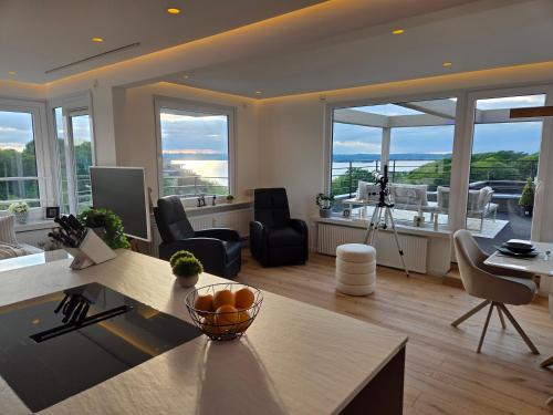 a living room with a table and some chairs and windows at Förde Loge - Traumblick & Spa in Glücksburg