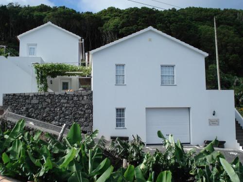 a white house with a stone wall and trees at PICO HOLIDAY RENTALS, Casa Do Avô Faidoca in Calheta de Nesquim