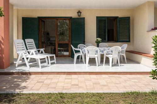 a patio with white chairs and a table on a patio at Hotiday Apartments Orosei in Cala Liberotto