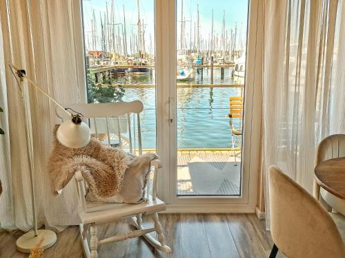 a rocking chair with a lamp and a view of a marina at Hausboot Yara am Steg 1D in Heiligenhafen