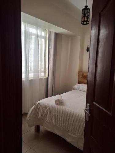 a small bedroom with a bed and a window at Serene 63 Luxe in Murangʼa