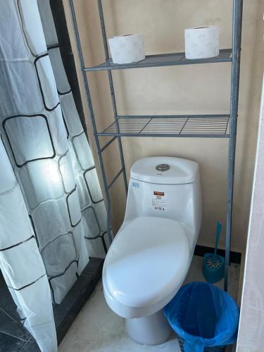 a bathroom with a white toilet and shelves at Villa Colibríes in Chelem