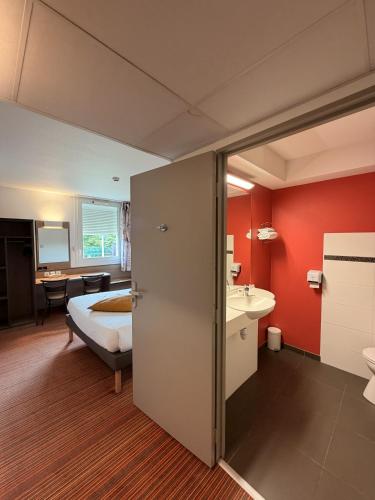 a hotel room with a bed and a bathroom at Hôtel Goodwood Caen Mémorial in Caen