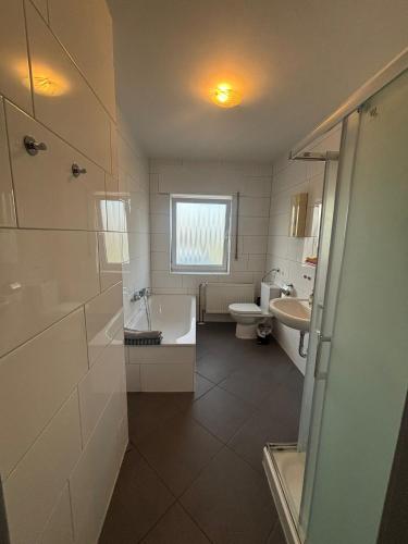 a bathroom with a tub and a toilet and a sink at Ferienwohnung Habichtweg in Elsdorf