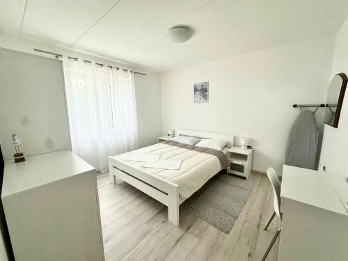 a white bedroom with a bed and a desk at Maver apartment in Mali Lošinj