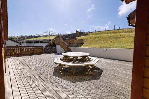 a picnic table on the deck of a house at Quoys Self Catering, Shetland in Lerwick