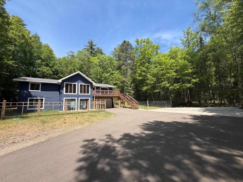 a blue house on a road in front of trees at Big St Germain Hideaway in Sayner