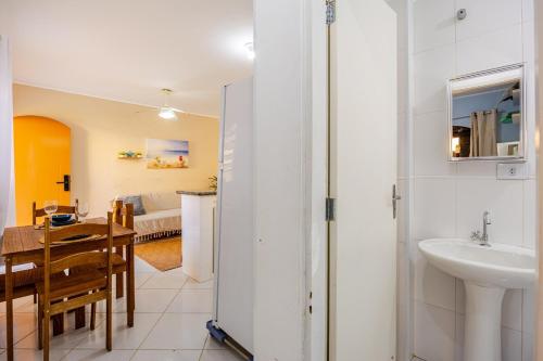 a bathroom with a sink and a dining room with a table at Casa a 500m da Praia do Sape in Ubatuba