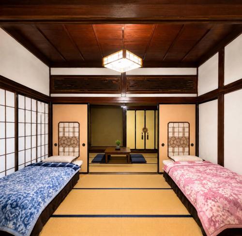 two beds in a room with a table at Guesthouse今井邸 in Tonami