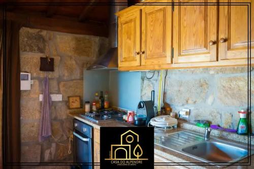 a small kitchen with wooden cabinets and a sink at Casa do Alpendre in Arco de Baúlhe