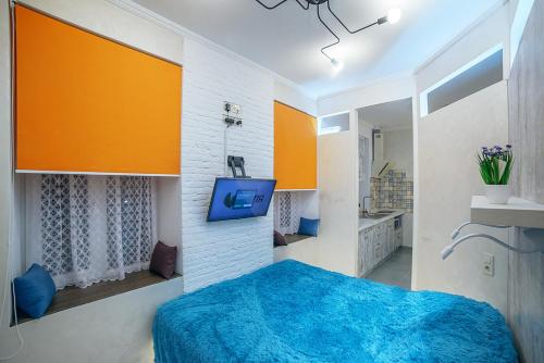 a bedroom with a blue bed and a tv on a wall at Apartment at Lyulki in Lviv