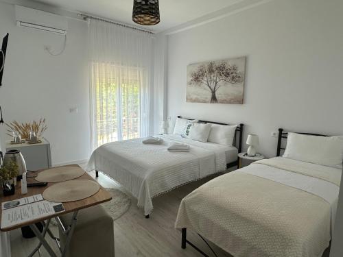 a white bedroom with two beds and a table at Ilvi Guesthouse in Gjirokastër