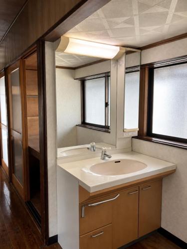 a bathroom with a sink and two windows at Guesthouse今井邸 in Tonami