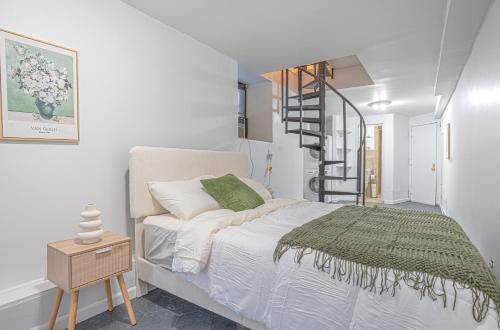 a white bedroom with a bed and a spiral staircase at Charm 2Bd in Upper East Side with Backyard in New York