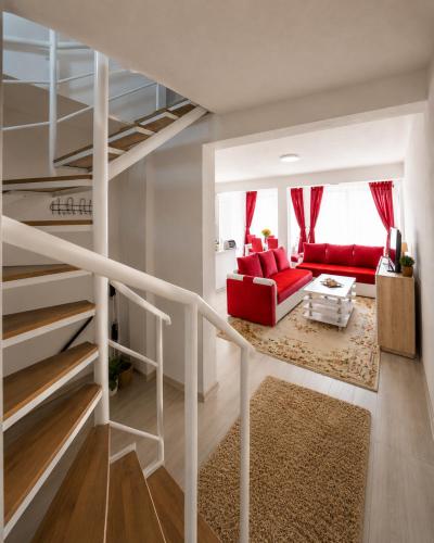 a living room with a red couch and a staircase at Planinska Oaza in Pale
