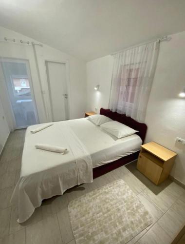 a bedroom with a large white bed and a table at Vila Ideal in Donji Štoj