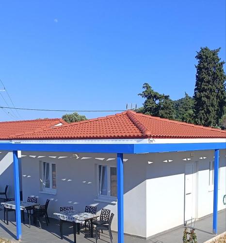 a building with a blue roof and tables and chairs at Agria Rigani Studios in Samos