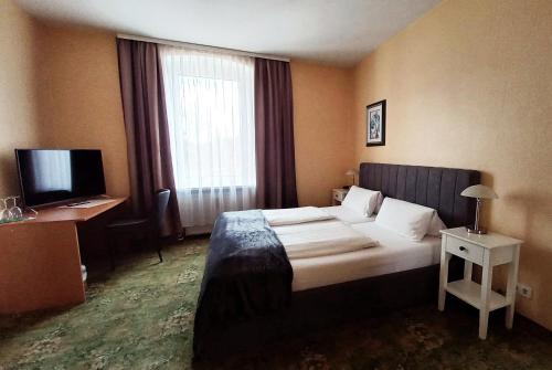 a hotel room with a bed and a television at Hotel Krone Lindow in Lindow