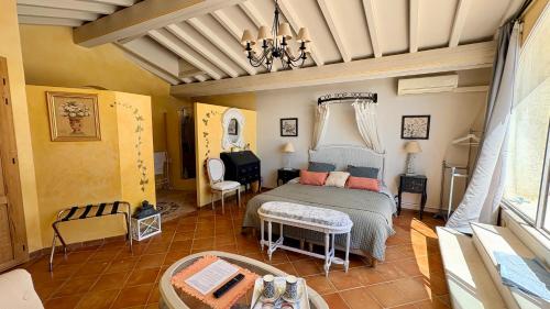 a bedroom with a bed and a chair and a table at Entre vignes et dentelles in Courthézon