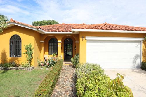 a yellow house with a white garage at Tamarindo Village in San Carlos