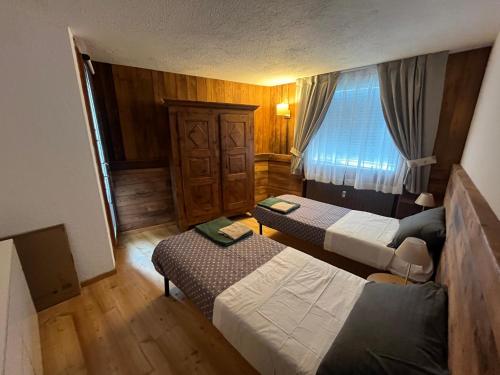 a small room with two beds and a window at Chalet Blanc le Refuge in Courmayeur