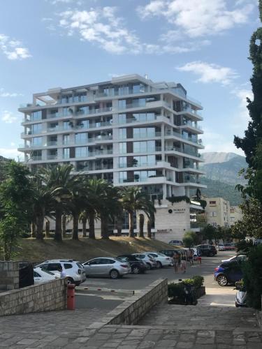a large white building with cars parked in a parking lot at Dukley residence Lux in Budva