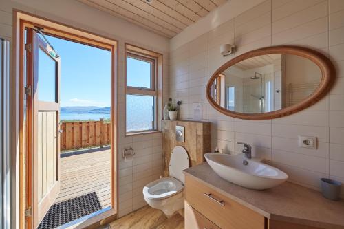a bathroom with a sink and a toilet and a mirror at Brekka in Akranes
