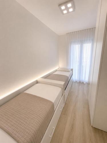a white room with two beds and a window at Haus Margarete - Agenzia Cocal in Caorle