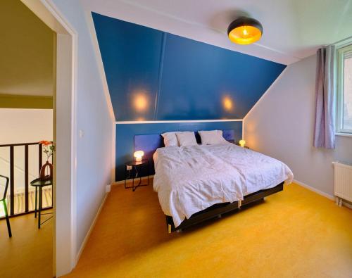 a bedroom with a blue wall and a bed at Gezinsvriendelijk natuurhuis De Kraanvogel in Appelscha