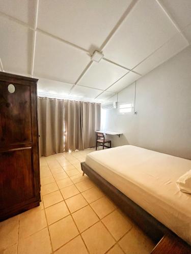 a bedroom with a bed and a wooden cabinet at 11 Residence Thalassa in Belle Mare