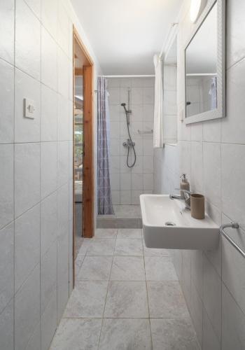a white bathroom with a sink and a shower at Villa Insula by Belmont Realty in Vela Luka
