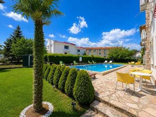 a palm tree and a swimming pool in a yard at Complex Sea & Sky next to the Beach ! in Kranevo