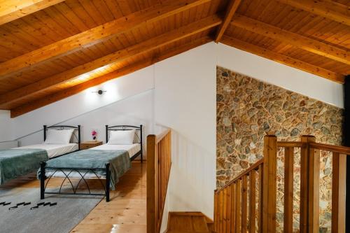 two beds in a room with wooden ceilings at Epi tis Stigos in Kalavrita