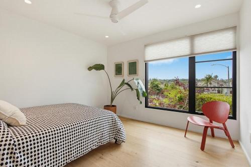 a bedroom with a bed and a window and a chair at Modern Encinitas Retreat in Encinitas