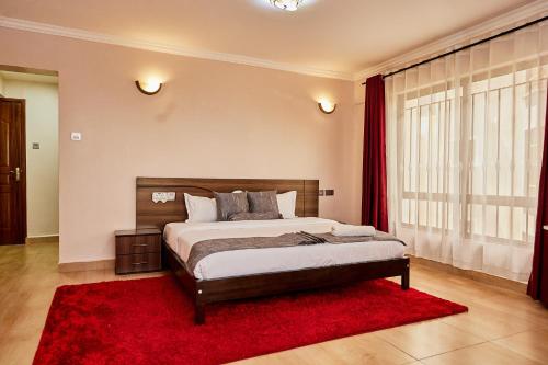 a bedroom with a large bed and a red rug at Lakeview 3Bedroom Condo with heated pool in Nakuru Town in Nakuru